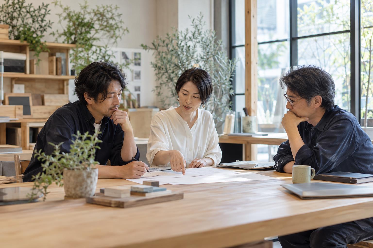 資料を囲んで採用について話し合う3人のイメージ（AI生成）